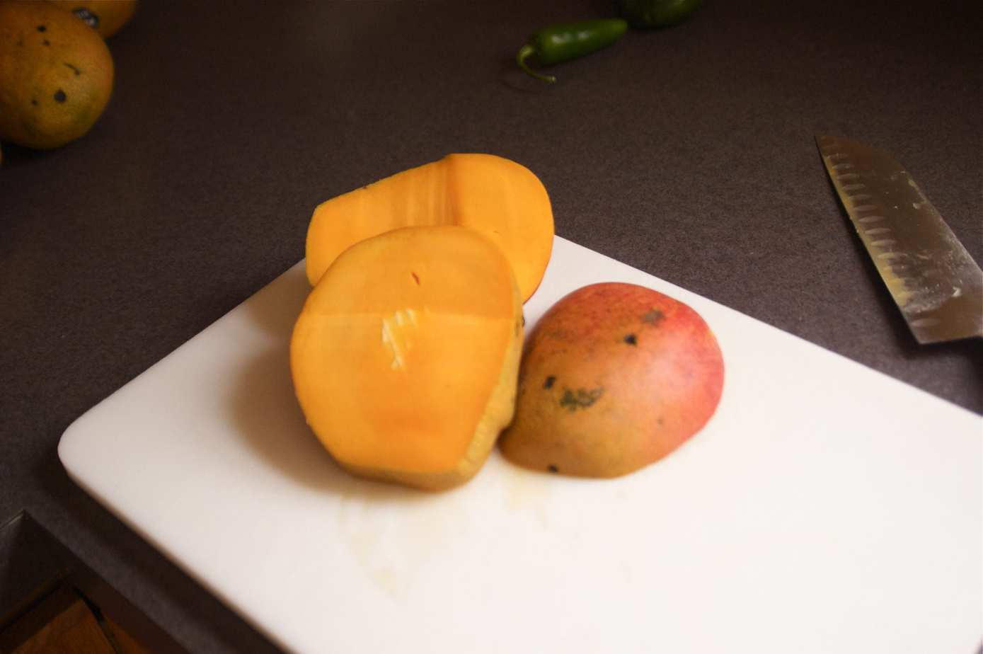 half of a mango on a cutting board