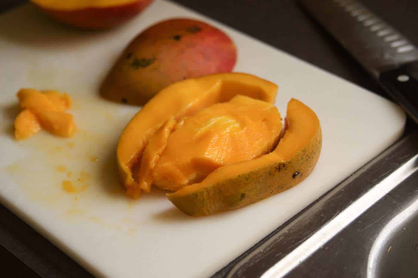 mango seed and pieces of a mango on a cutting board