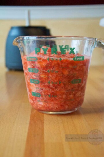 A measuring cup filled with freezer strawberry jam.