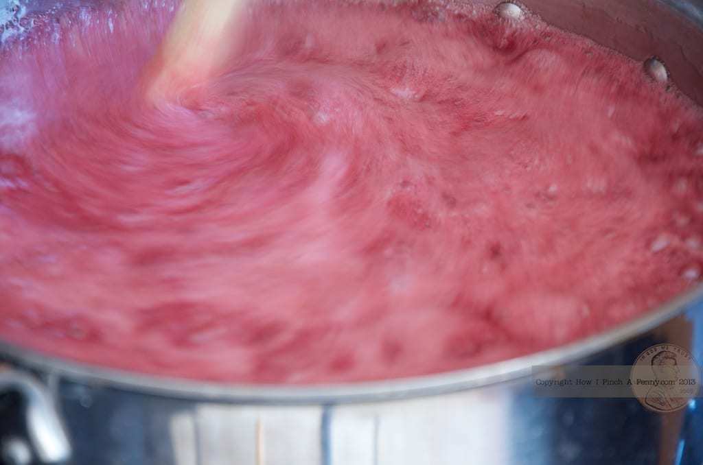 Making Cherry Jam - A pot of red liquid being stirred with a wooden spoon.