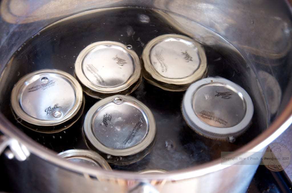 A pot filled with metal cans on a stove, used for making cherry jam.