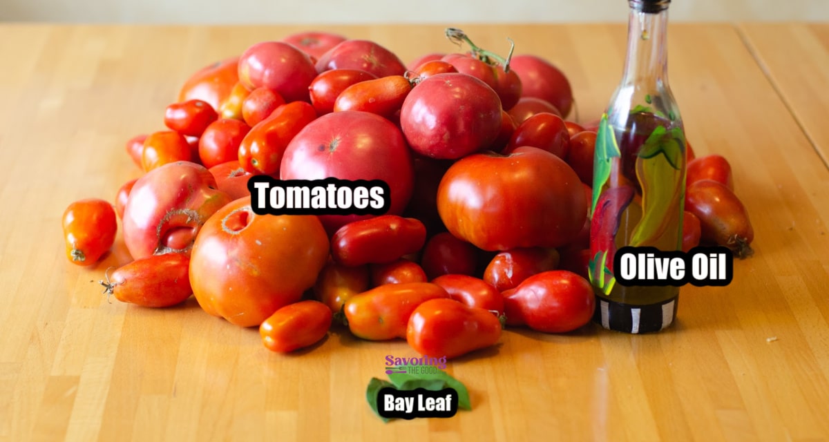 A pile of tomatoes with labeled text and a bottle of olive oil sit on a rustic wooden table, accompanied by a bay leaf in the foreground. The scene hints at the creation of homemade tomato paste.