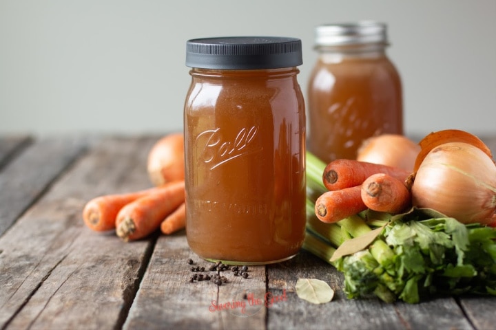 horizontal image of Vegetable Stock with vegetables surrounding the jar