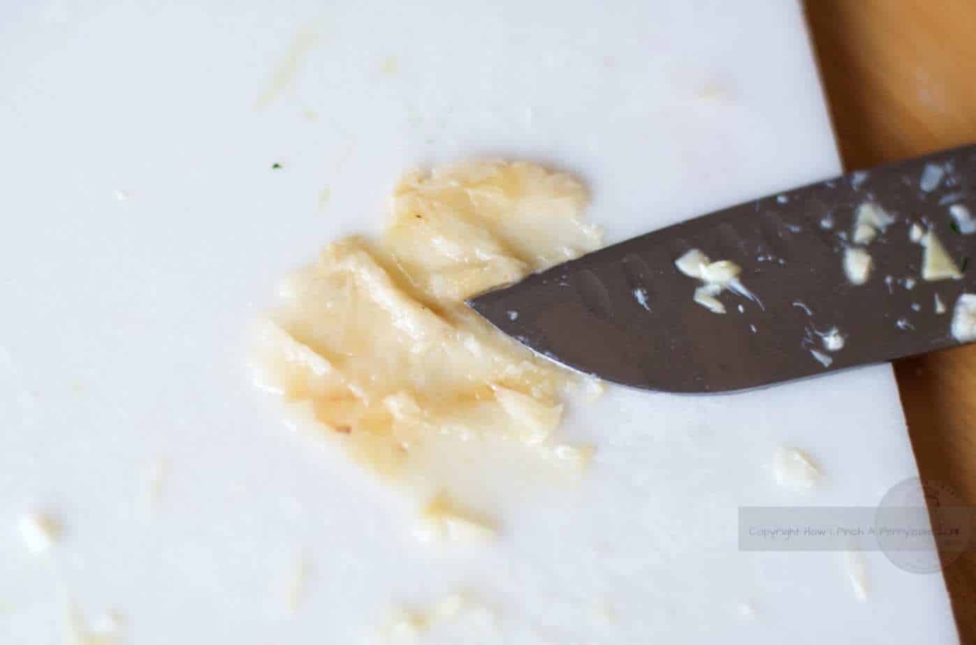 smashed roasted garlic under a knife