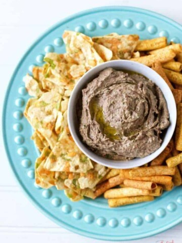 A bowl of gluten-free hummus and chips on a blue plate.