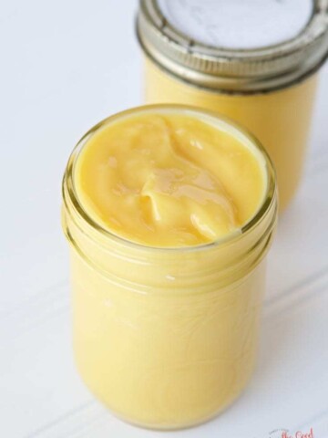 Two jars of lemon butter with Sous Vide Lemon Curd on a white table.