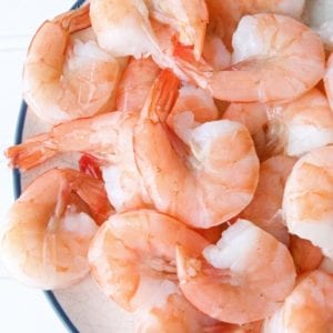 Explore a tantalizing sous vide shrimp recipe presented on a rustic wooden table, showcasing beautifully cooked shrimp delicately placed on a sleek white plate.