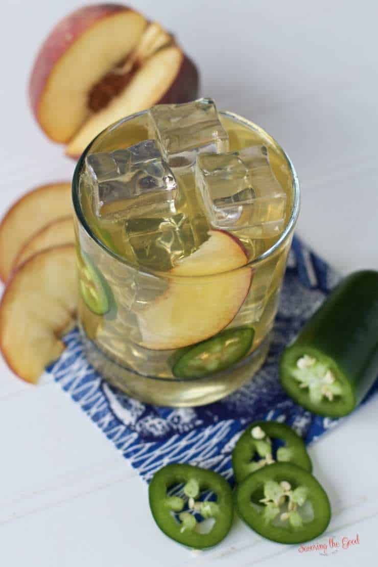 This spicy peach bourbon smash cocktail is a delicious summer bourbon cocktail made with fresh peaches and smashed jalapeños. Sweetened with jalapeño infused honey, this peach whiskey drink goes down smooth and ends with a kick of heat. Summer isn't complete with out a peach whiskey drink. #peachcocktail #bourbonsmash ##summercocktail #bourboncocktail #peachsmash