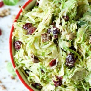 A bowl of Brussels sprout slaw with cranberries and nuts.