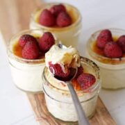 Creme brulee dessert in jars with whipped cream and raspberries.