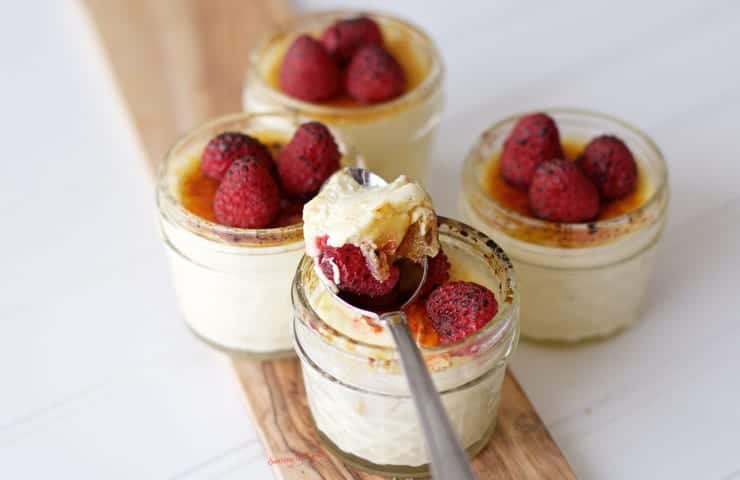 Creme brulee dessert in jars with whipped cream and raspberries.