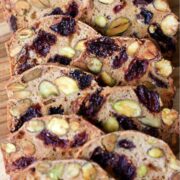 Almondina Pistachio and Dried Cherry Crisp on a bamboo cutting board shingled out for display.