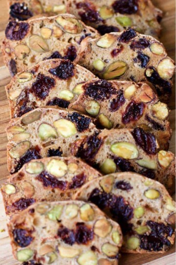 Almondina Pistachio and Dried Cherry Crisp on a bamboo cutting board shingled out for display.