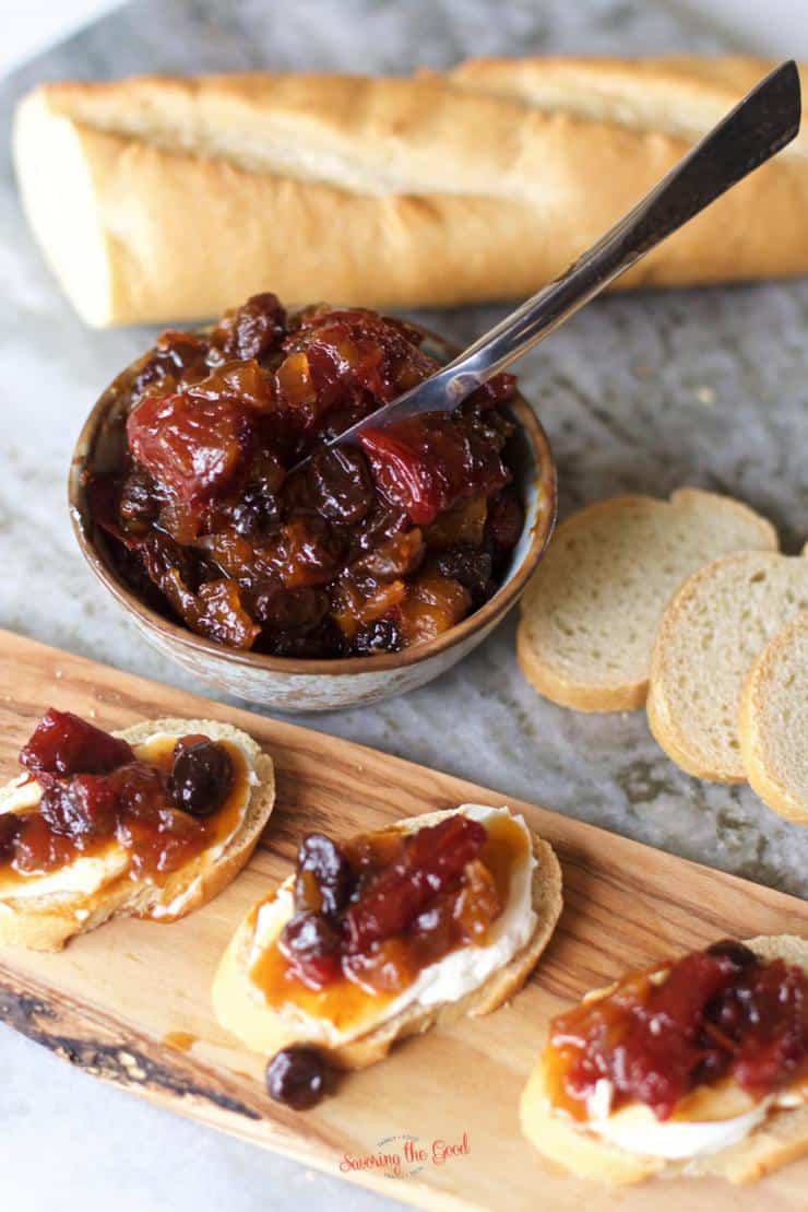 A wooden board with bread and cranberry jam, topped with tomato jam.