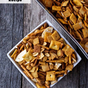 Buffalo Chex Mix in a bowl with the pan above on a wooden surface