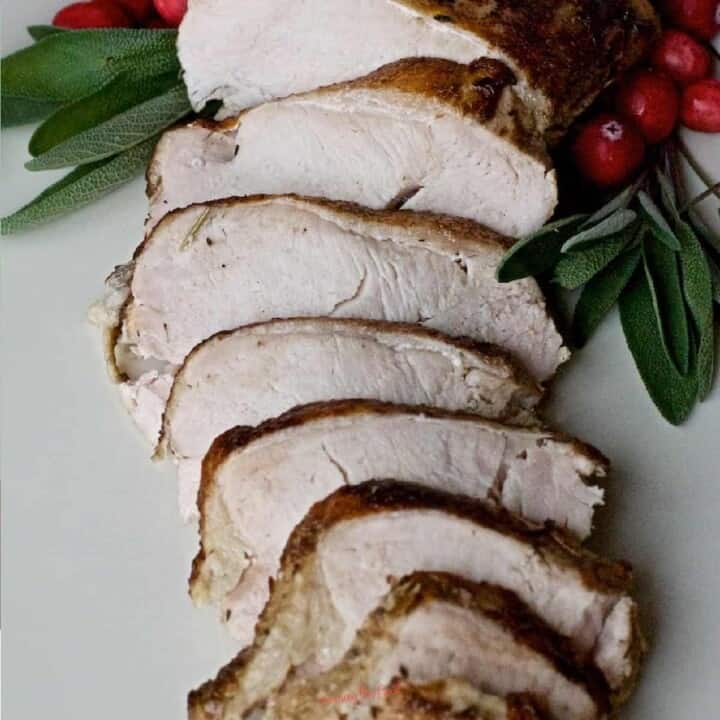 Simple turkey breast recipe with cranberries and sage on a white plate.