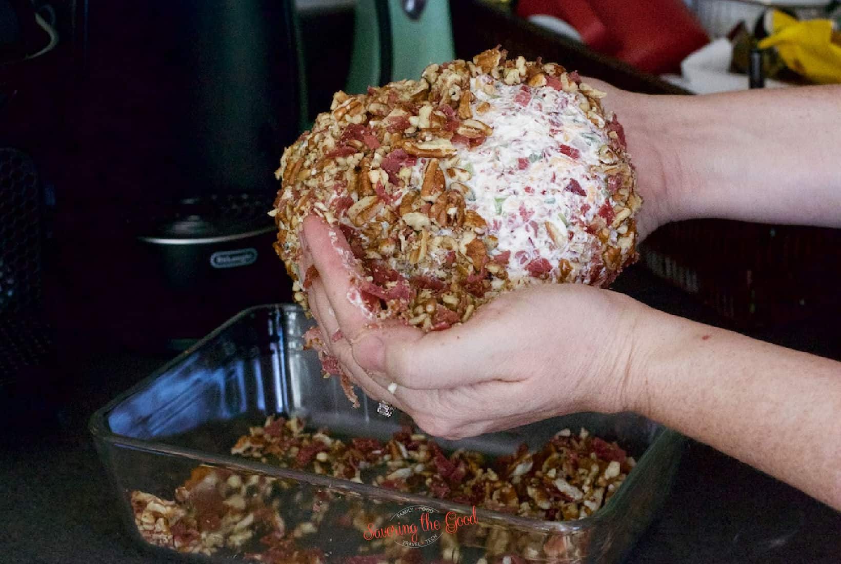 showing how to add pecans to the outside of a Cheese Ball
