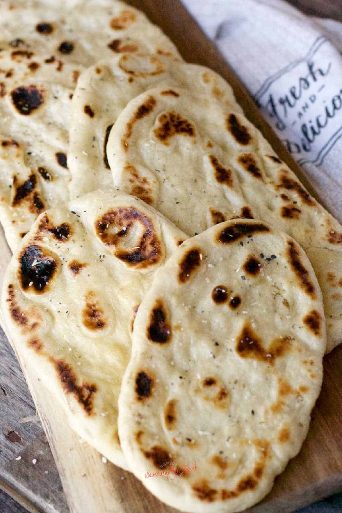 8 pieces of baked Naan Bread on a wooden cutting board