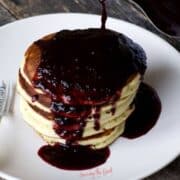 A stack of pancakes with homemade blueberry syrup on top.