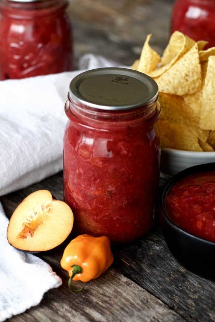 Plum Habanero Salsa in a ball canning jar with chips in the background