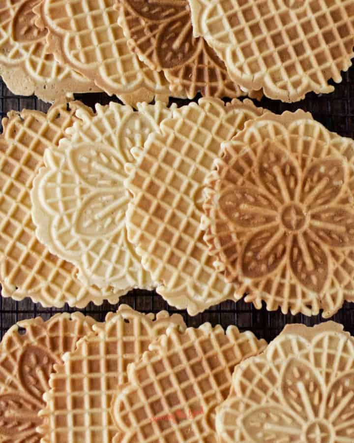 lemon pizzelle cookies of different doneness on the cooking rack