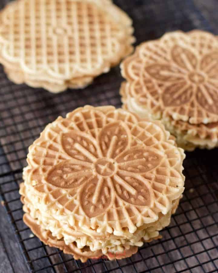 3 stacks of lemon pizzelle cookies on a cooling rack