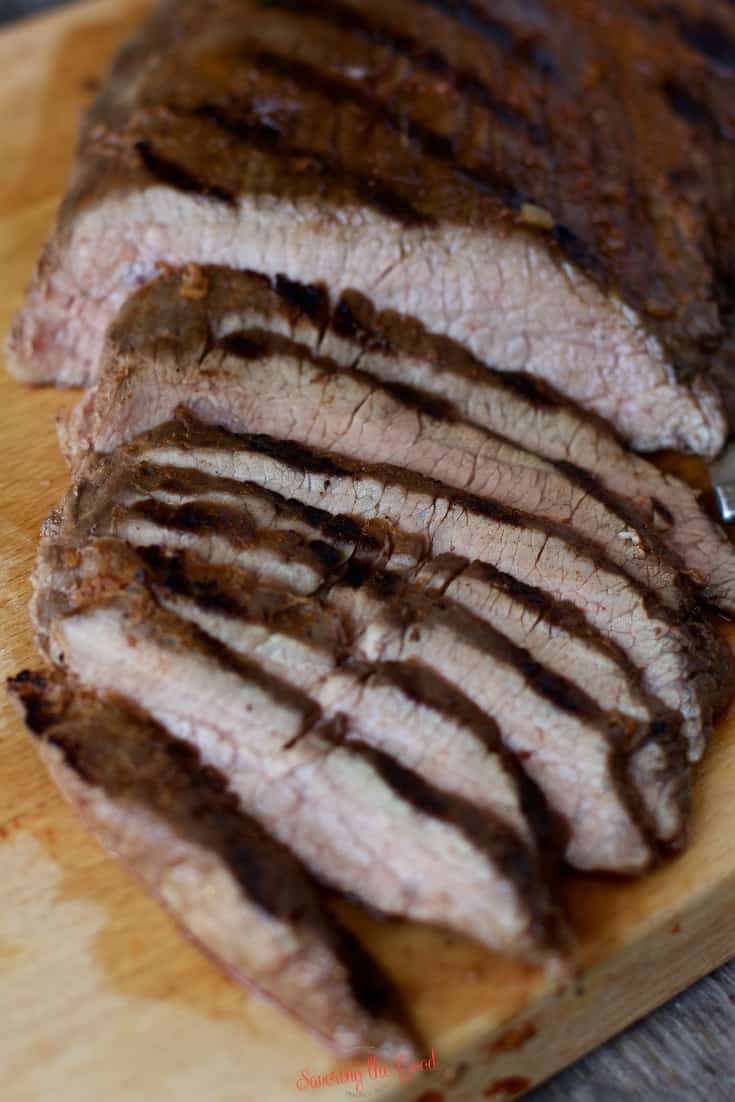 vertical image of sous vide flank steak sliced on a wooden cutting board