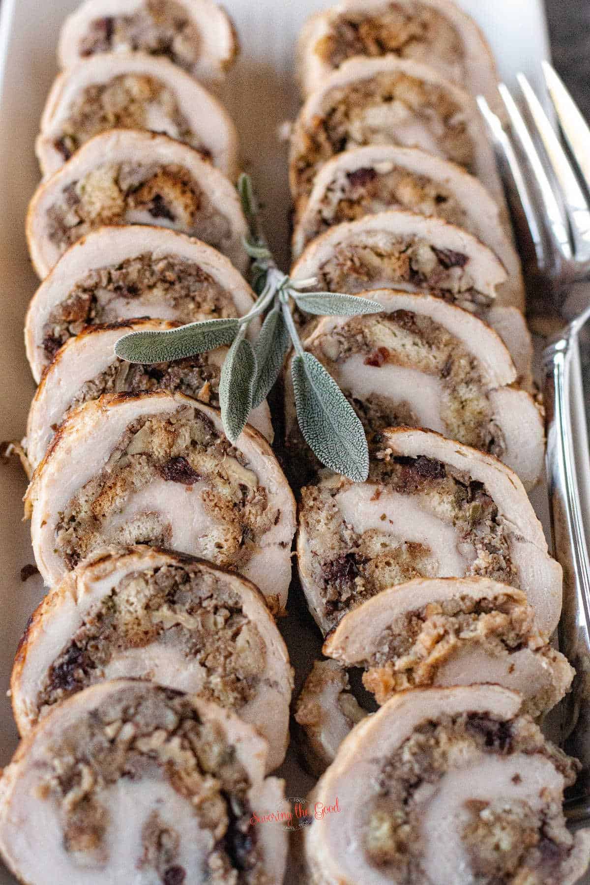 vertical image of 2 sliced turkey roulade with sage stuffing filling