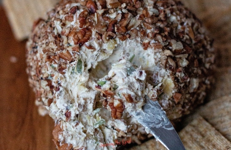 pineapple cheeseball with a serving spatula carving out a portion