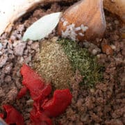 Ground beef browning in a pot with onions, dried herbs, tomato paste, and a bay leaf, stirred with a wooden spoon-an aromatic base for hearty Lasagna Soup.