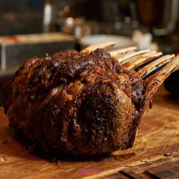 A Christmas roasted rack of lamb on a wooden cutting board.