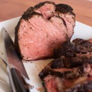 sous vide prime rib on a white platter sliced to show the inside of the meat