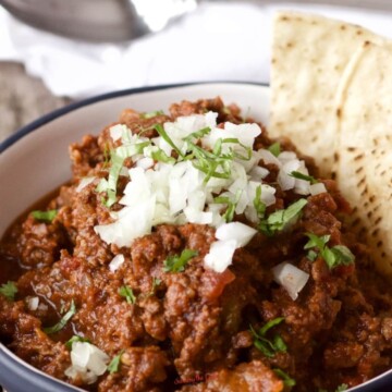 bowl of chili without beans garnished with chopped onions