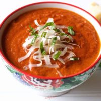 oven roasted tomato soup in a bowl with cheese and basil garnish, square image