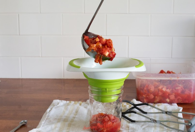 adding fresh tomatoes to a canning jar