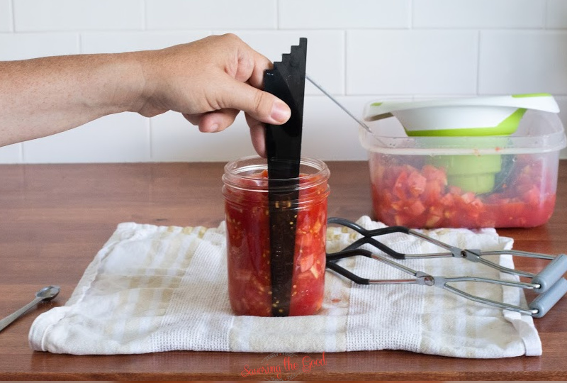 removing the airbubbles from a canning jar of diced tomatoes