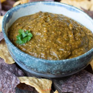 roasted tomatillo salsa verde in an earthenware bowl surrounded by tortilla chips