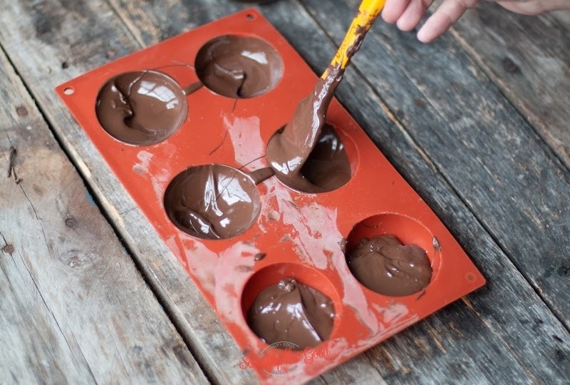 spreading chocoalte in silicone molds for hot chocolate bomb