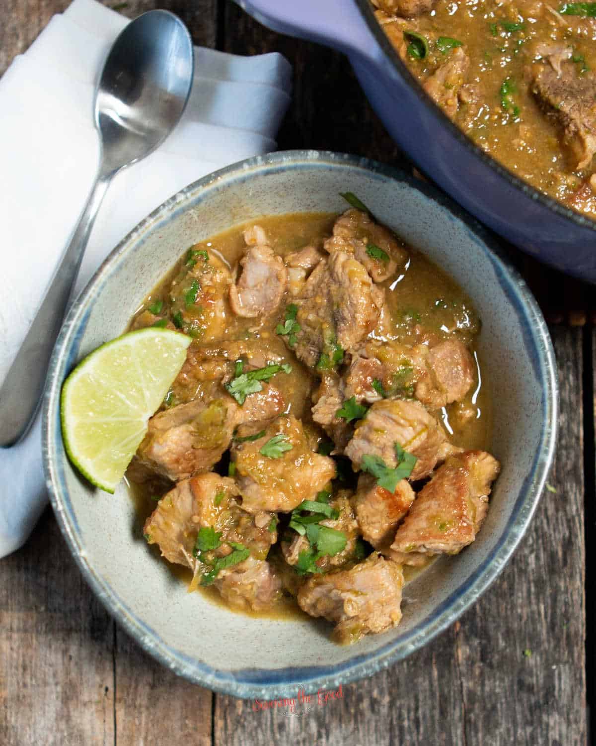 Chili Verde in a bowl with the pot in the background with the rest of the servings