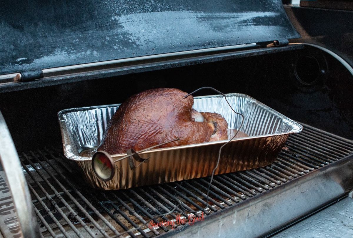 Whole smoked turkey on the grill with thermometer in it horizontal image