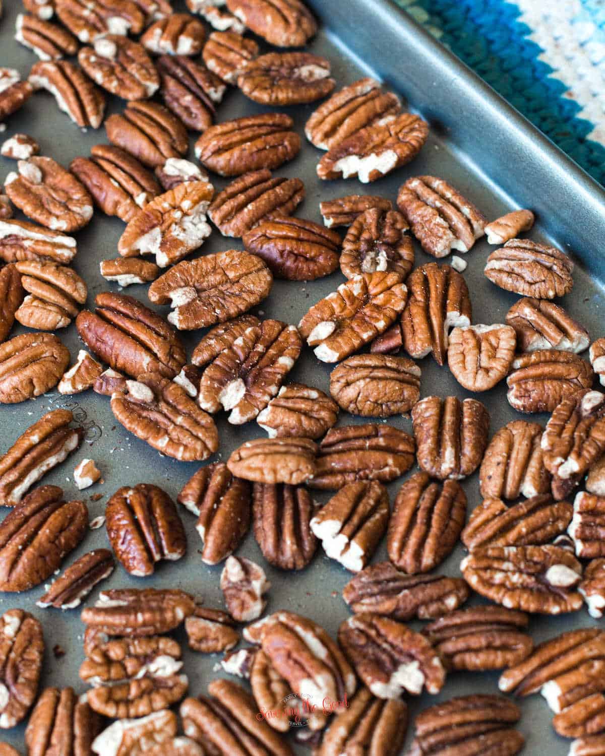 toasting pecans on a non stick sheet tray with a pot holder in the corner vertical image