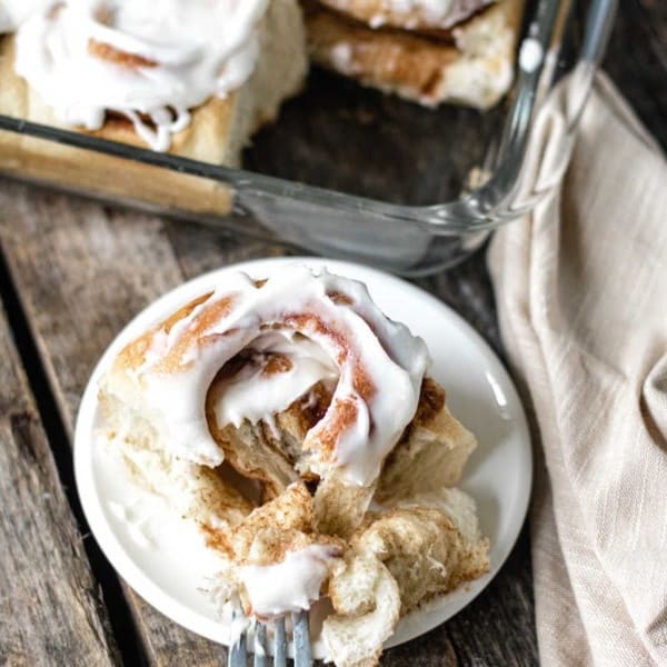 Rhodes Cinnamon Rolls with icing on a plate and fork pulled apart