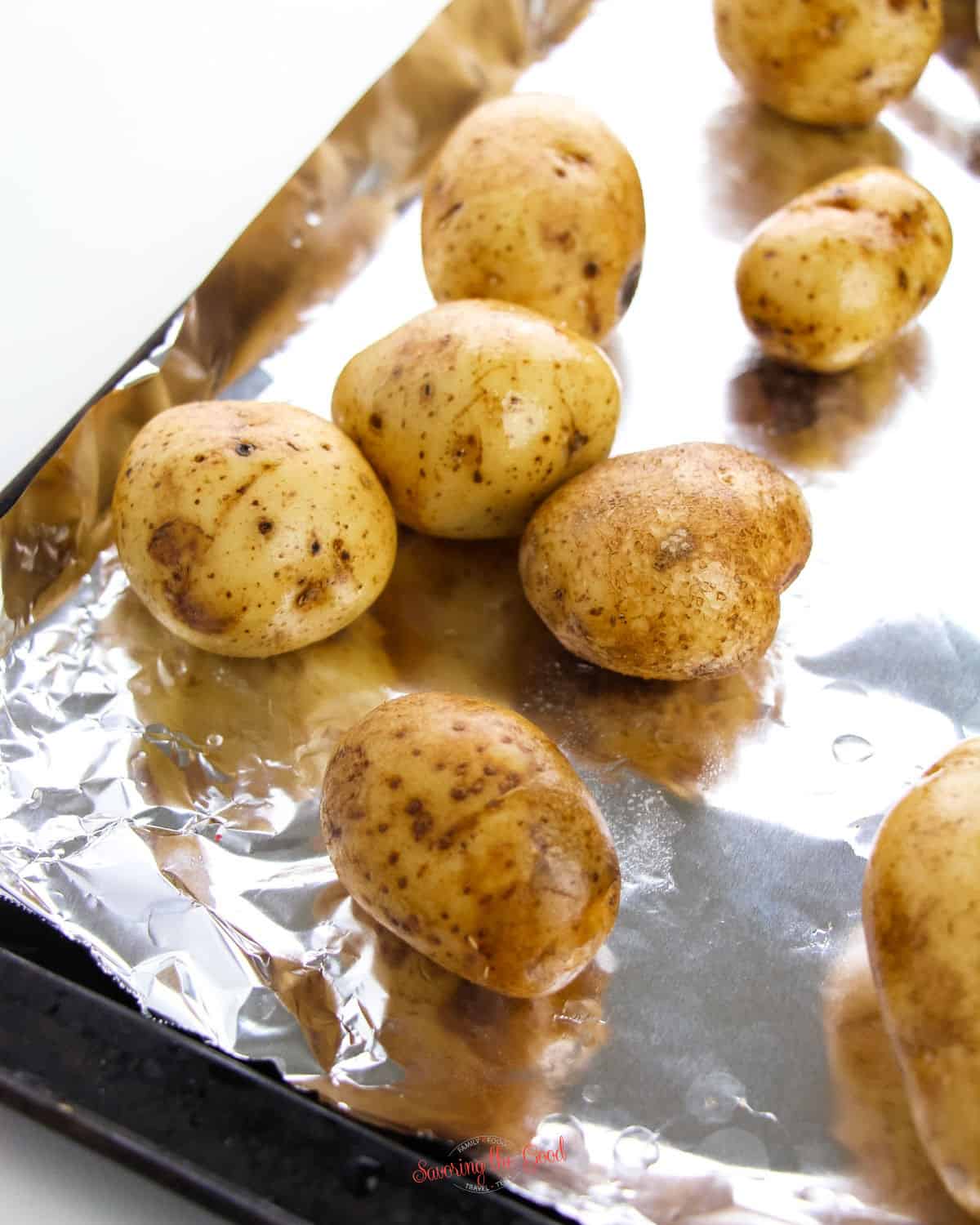 whole potatoes to be baked on a foil lined baking sheet