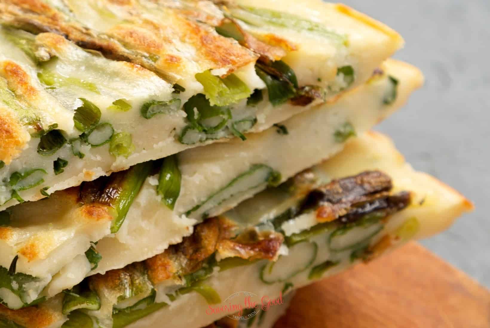A stack of asparagus pancakes on a wooden cutting board. jeon.