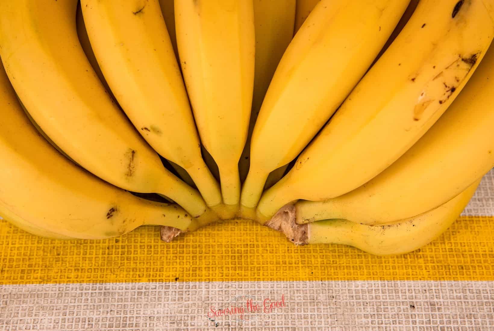 A bunch of xiangjiao bananas on a yellow and white striped cloth.