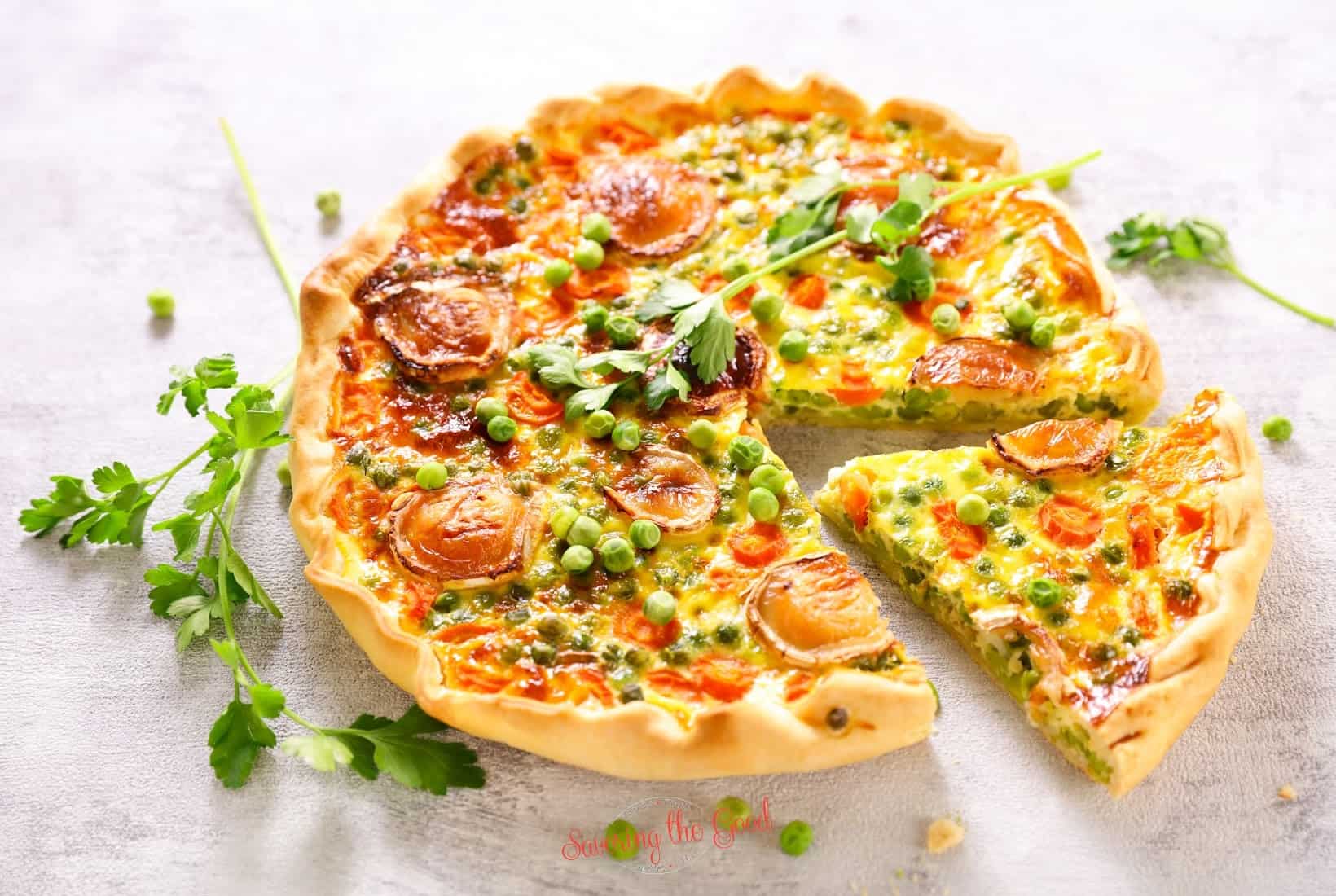 A quiche with peas and carrots on a white background.