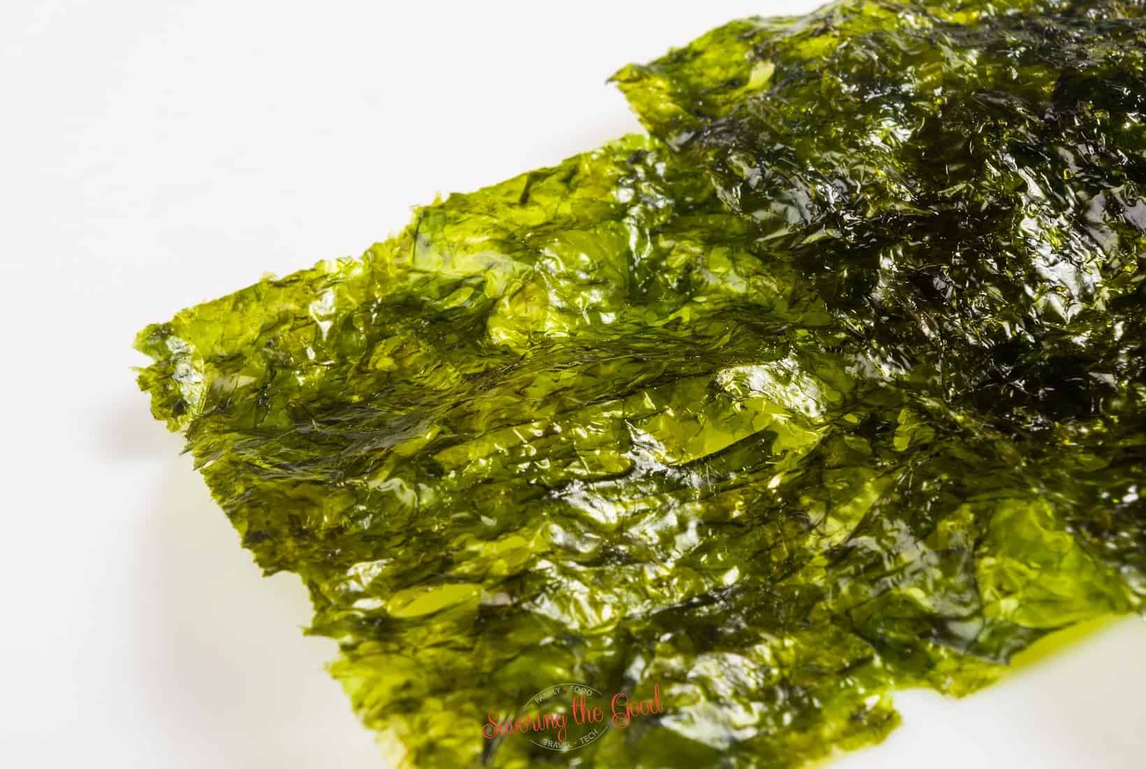 A piece of green seaweed on a white surface.