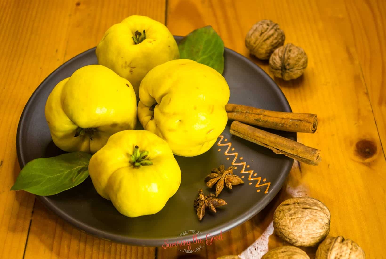 A plate of yellow quince fruits and nuts on a wooden table.
