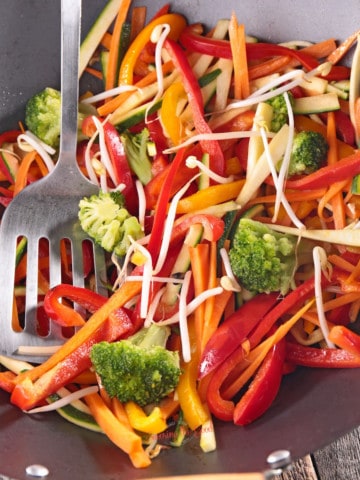 Stir fried vegetables in a wok with a fork.