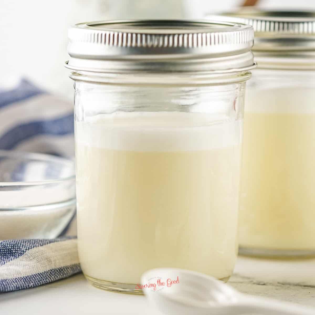 Two mason jars filled with sweetened condensed milk and a spoon.
